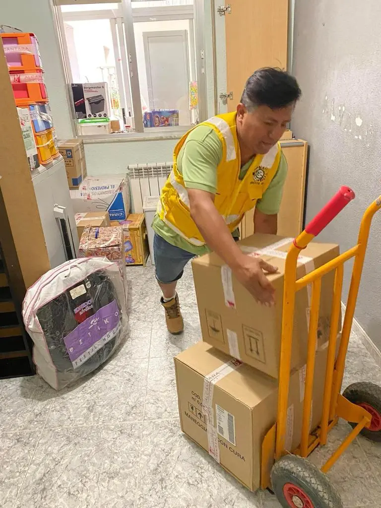 Operario con chaleco sube cajas de mudanza con una carretilla